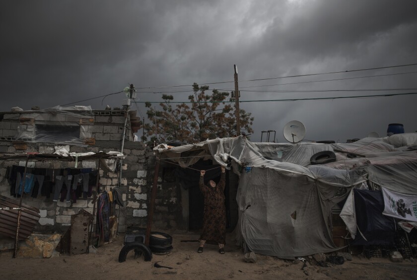 A Palestinian woman checks the nylon cover on her roof in a poor neighborhood of Khan Younis, in the Gaza Strip.