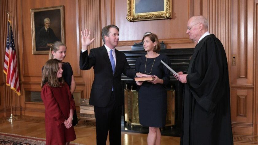 Retired Justice Anthony M. Kennedy, right, administers the judicial oath to Judge Brett Kavanaugh in the Justices' Conference Room of the Supreme Court Building, with Kavanaugh's wife and daughters looking on.