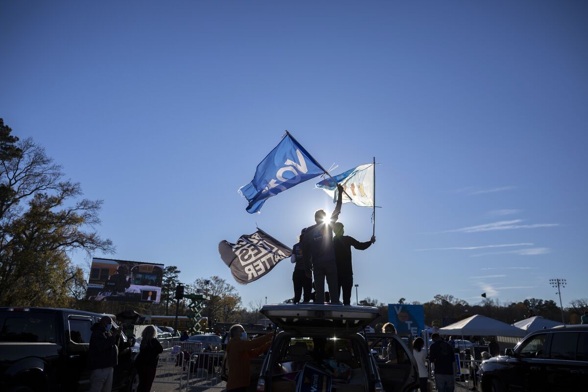 Supporters wave flags as they wait for Vice President-elect Kamala Harris at a drive-in rally in Savannah.