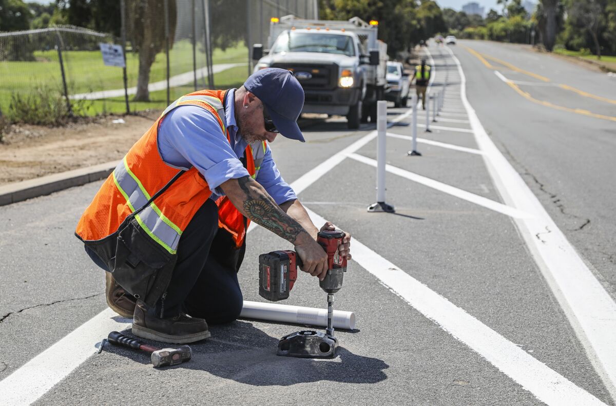 A San Diego Transportation Department worker installs posts along a bike lane on Pershing Drive in Balboa Park September 29.