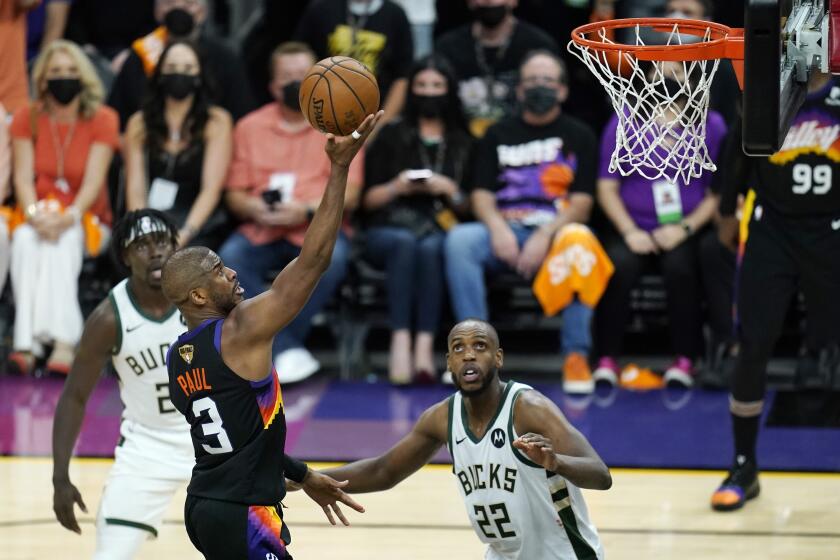 Phoenix Suns guard Chris Paul (3) scores as Milwaukee Bucks forward Khris Middleton (22) and Bucks guard Jrue Holiday, left, look on during the second half of Game 1 of basketball's NBA Finals, Tuesday, July 6, 2021, in Phoenix. (AP Photo/Ross D. Franklin)