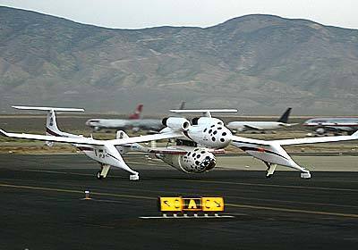 At sunrise, SpaceShipOne and its spider-like mother ship aircraft taxi down the runway.