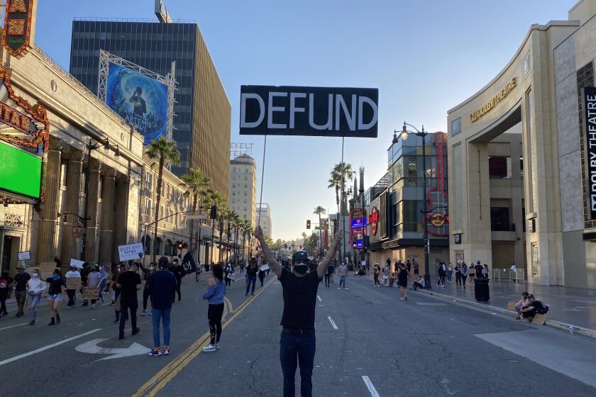 A protester holds up a sign calling for the LAPD to be defunded in Hollywood on June 7, 2020.