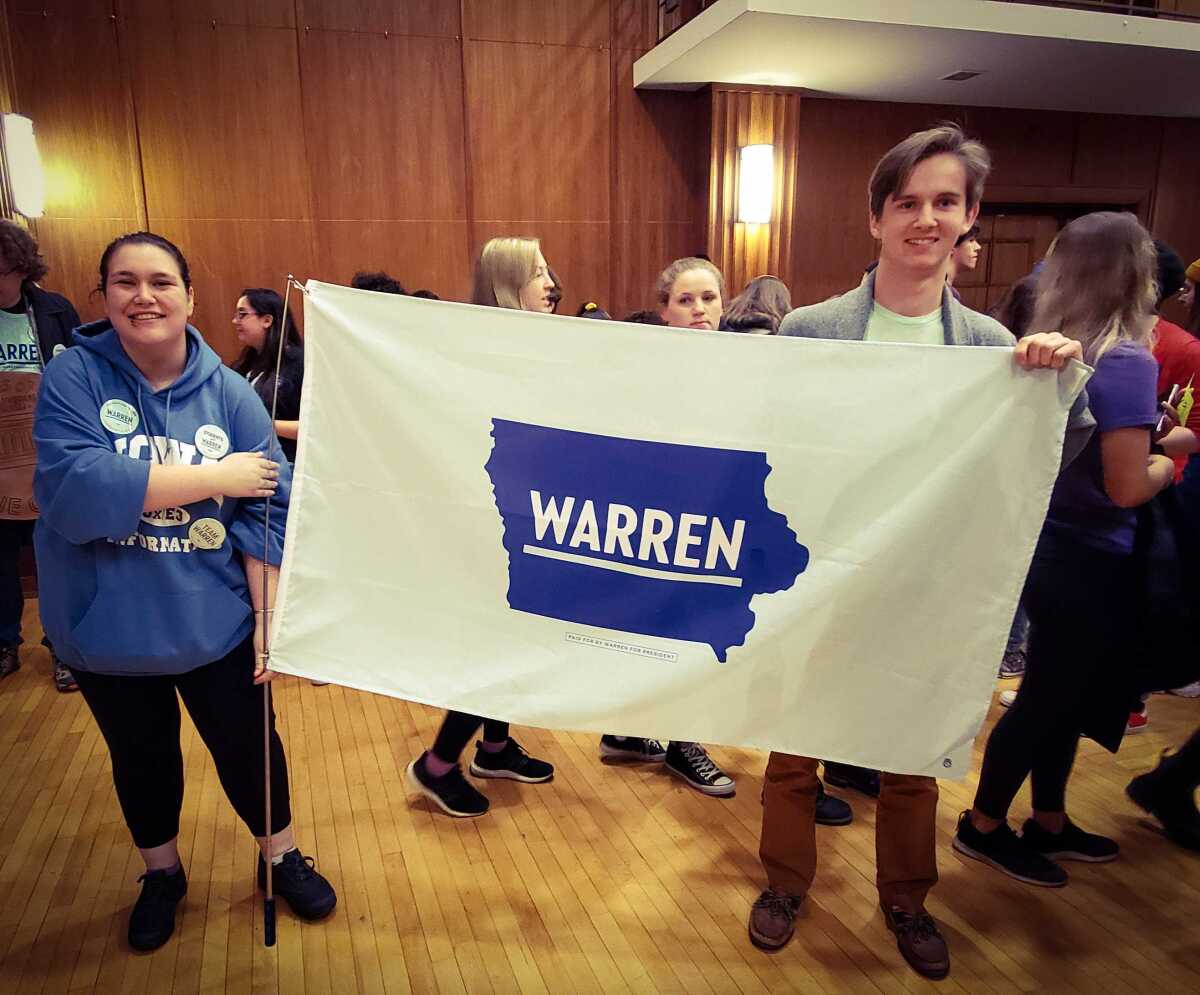 Shayla Ides, 19, and Oskar Kaut, 18, hold up a flag in support of Massachusetts Sen. Elizabeth Warren at the University of Iowa on Monday.