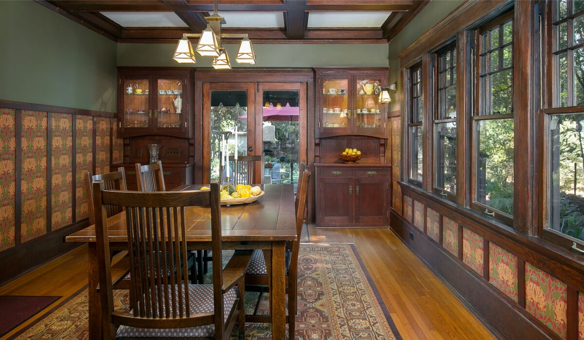 The 1910 Craftsman has a dining room with a bank of windows overlooking greenery and built-in cabinetry.