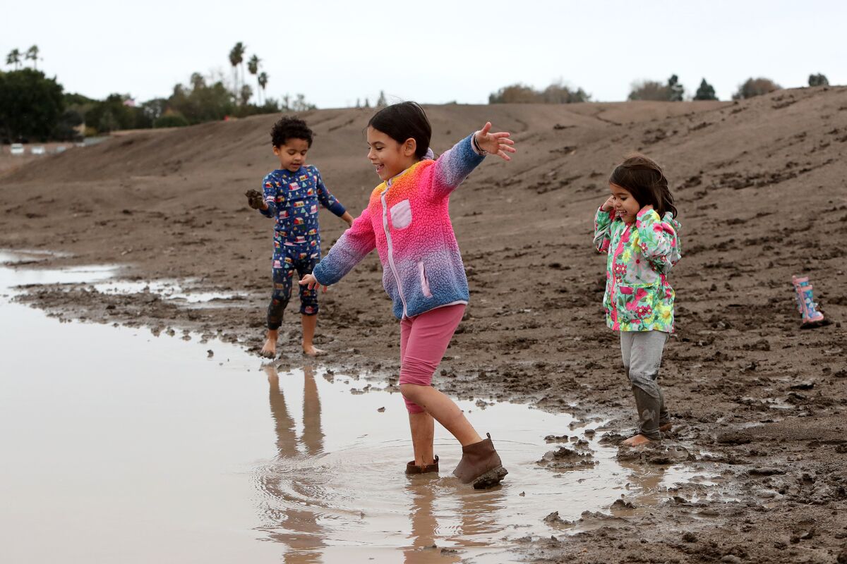 The Applebee siblings, Crusade, 4, left, Selah, 6, center, and Weslee, 3, right, play in a rain puddle on Tuesday.