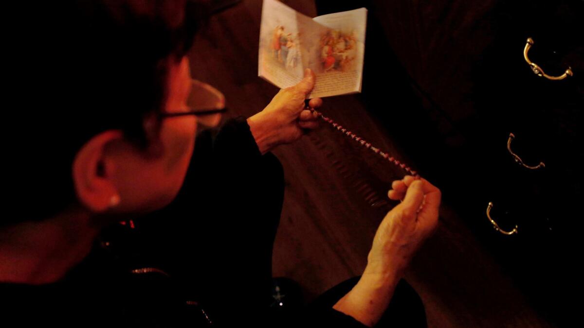 Zenaida Jose, 67, prays the rosary in her studio apartment.