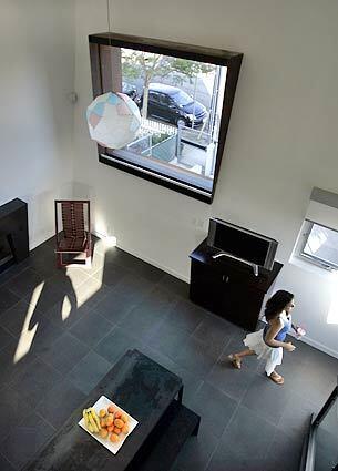 Judy Premingers daughter Liza walks across the main living area on the first floor which achieves a spare aesthetic with white walls and dark Inca basalt flooring. (Christine Cotter./.LAT)