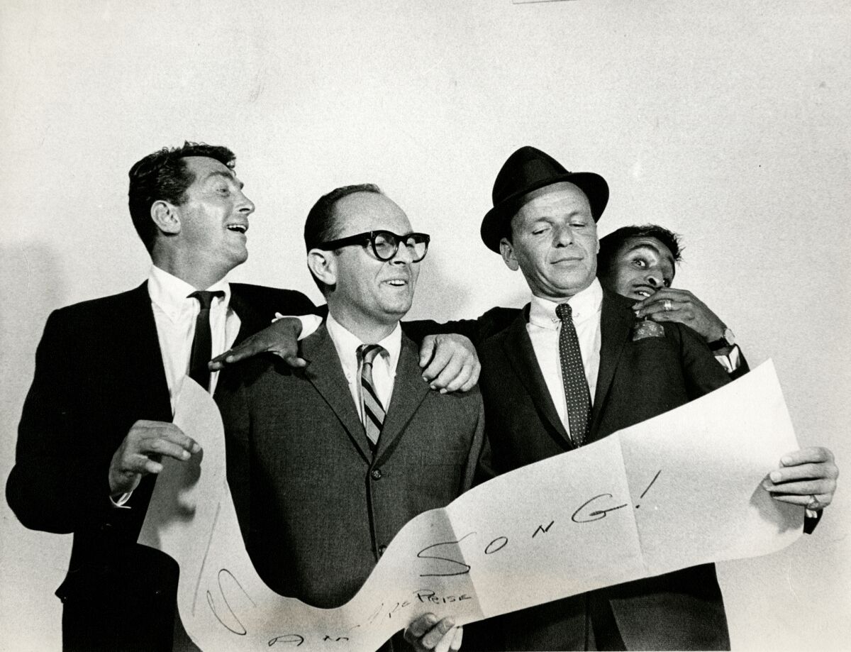 Four men smile as they stand together and hold up a long sheet of paper.