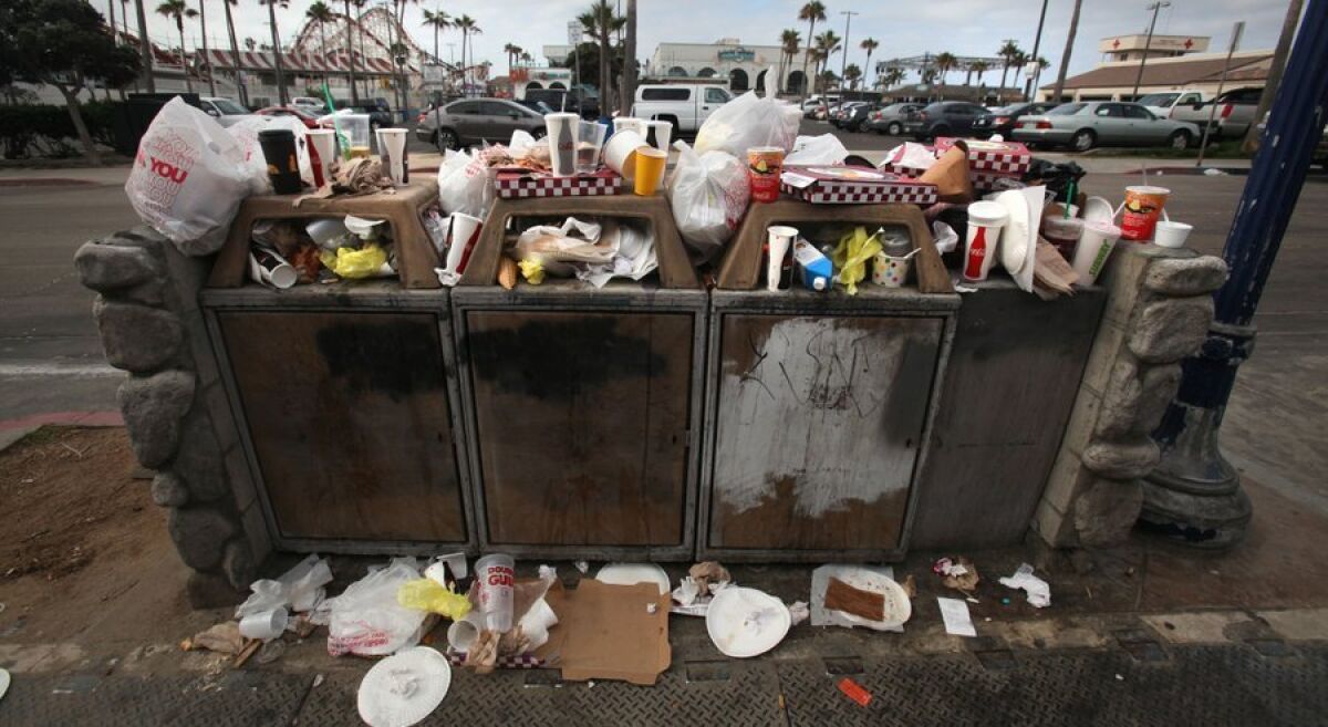 Trash, including plenty of plastic bags, overflows from bins at Belmont Park in Mission Beach.