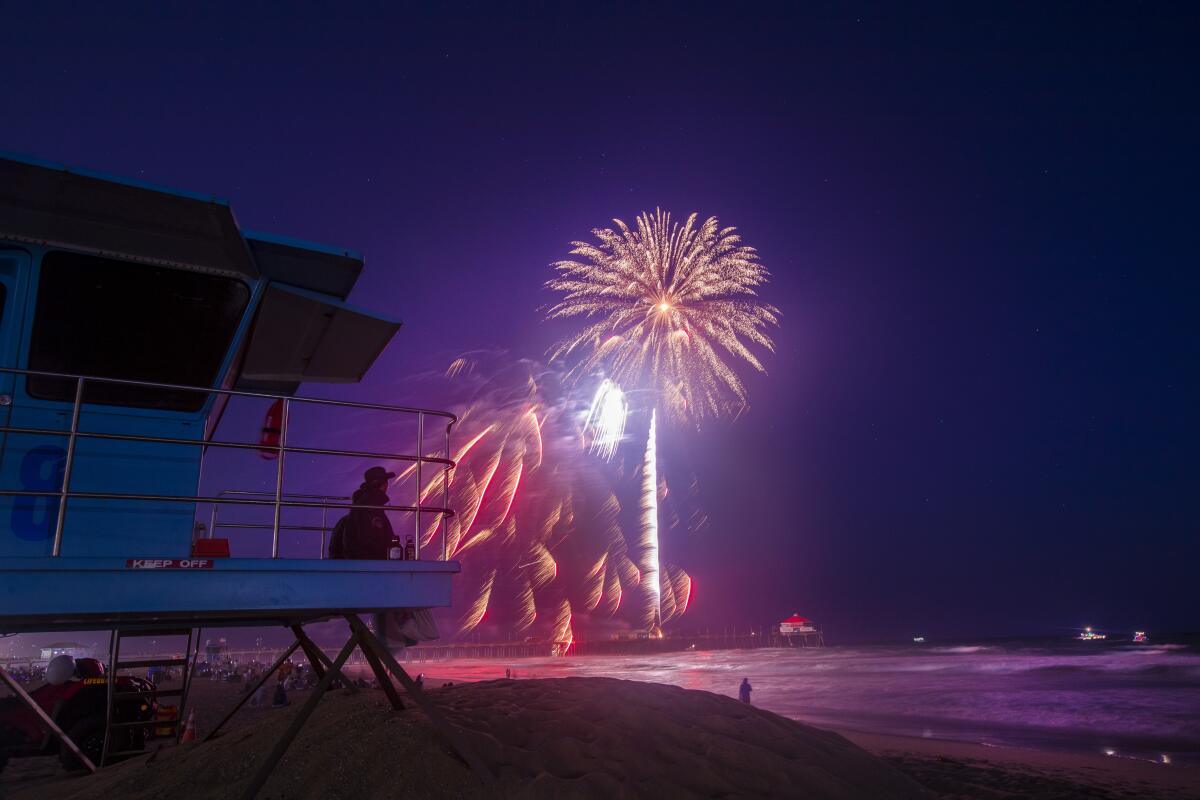 Huntington Beach lifeguards watch fireworks over the ocean on the Fourth of July.