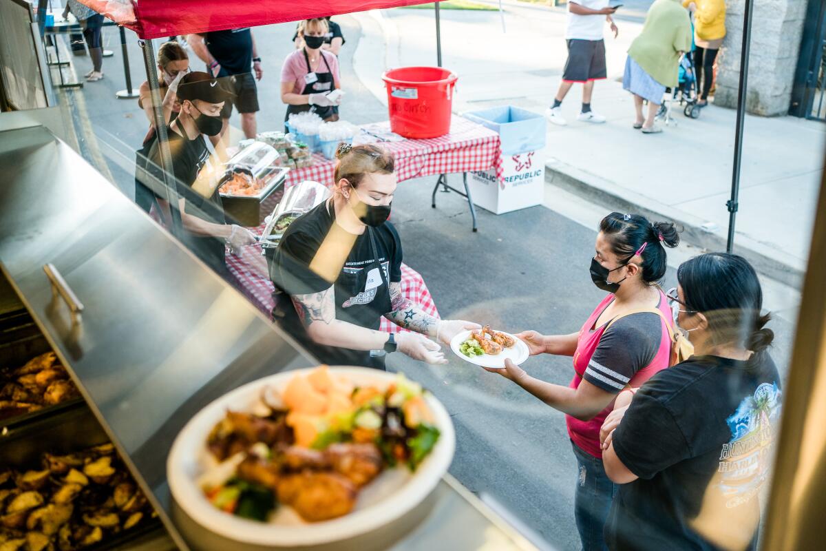 Bracken's Kitchen employees serve food at a food truck feeding event.