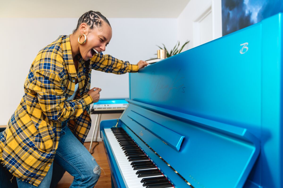 Alicia Keys is shown with the Steinway & Sons piano she is auctioning off.
