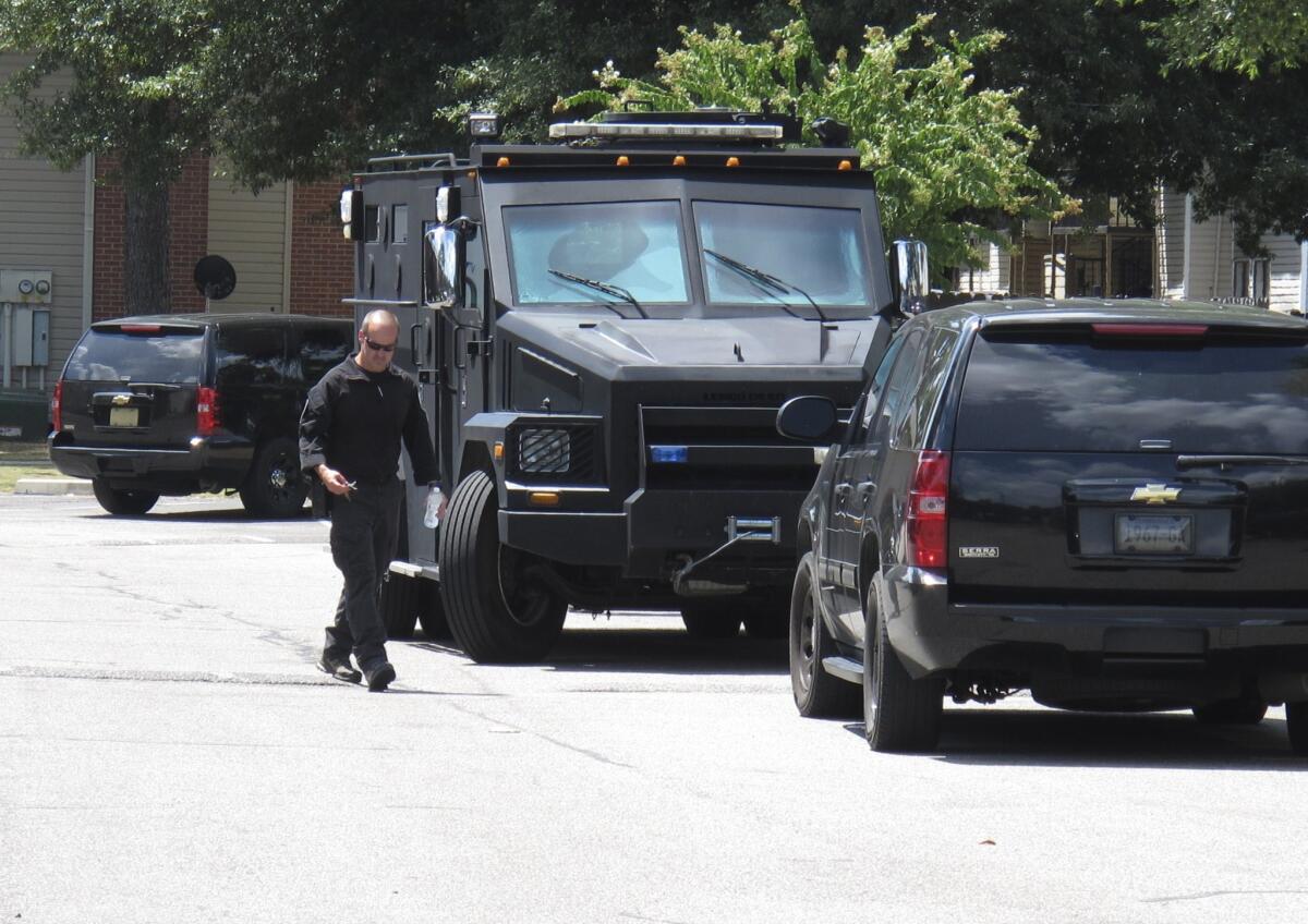 A police officer walks by an armored truck during a search of an apartment complex on Aug. 2, 2015, in Memphis, Tenn. Police were looking for a suspect in the fatal shooting of Memphis officer Sean Bolton, who was fatally shot Saturday night.