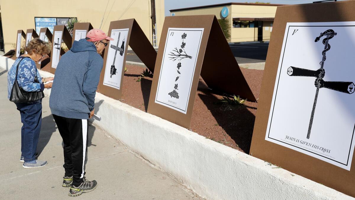 First United Methodist Church member Sharon Canfield invited her neighbor Carlos Messerschmidt to view the public art installation "Stations in the Street" on Friday outside the Costa Mesa church.