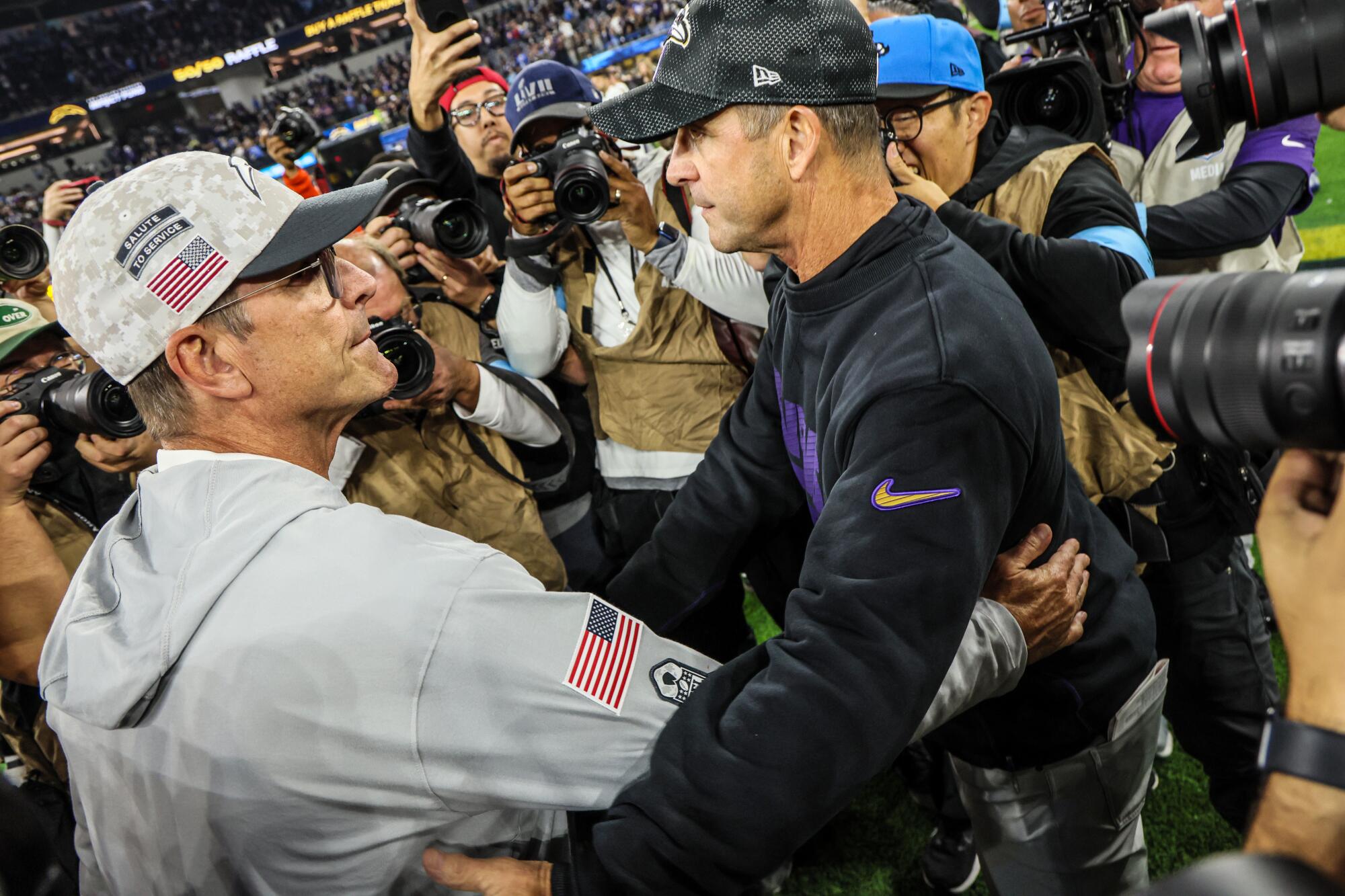 Chargers coach Jim Harbaugh (left) meets brother John, coach of the Ravens, after Baltimore's 30-23 victory.