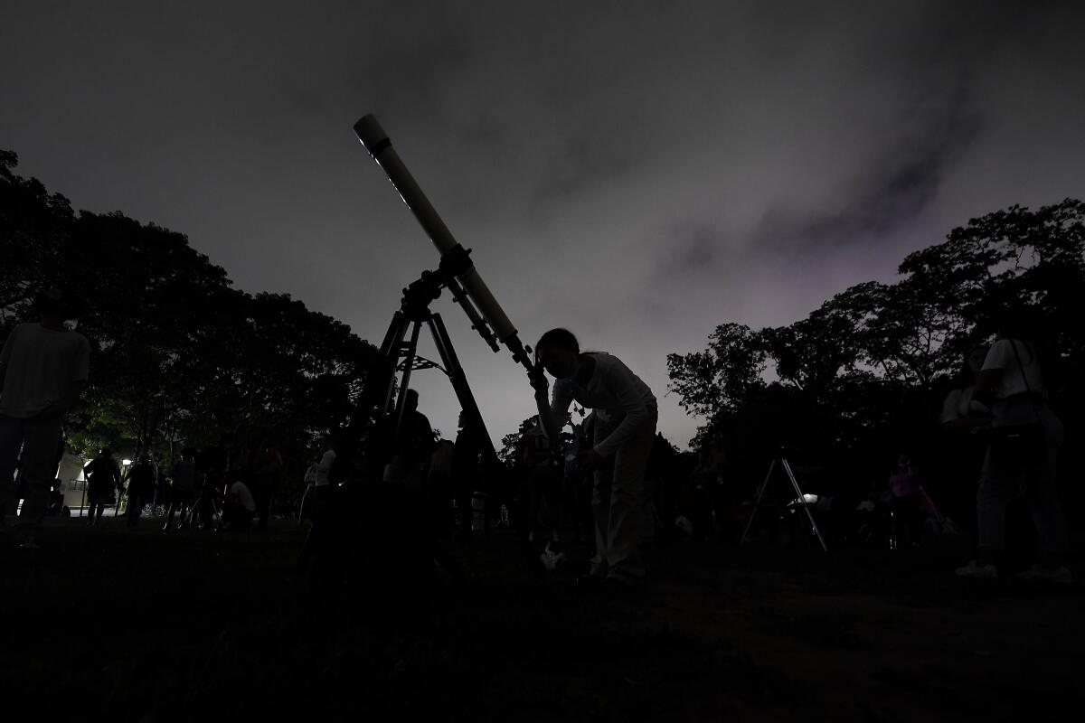 A person looks at the night sky through a telescope 