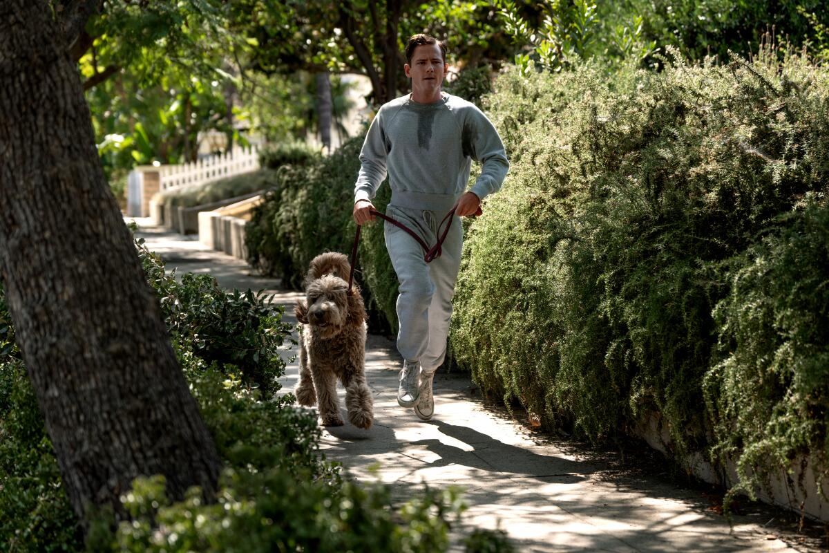 Actor Lewis Pullman runs with a dog in a scene from "Lessons in Chemistry."