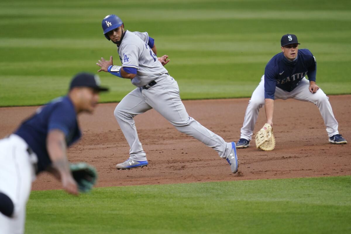 Dodgers' Keibert Ruiz takes off from first base between Seattle Mariners pitcher Taijuan Walker and first baseman Evan White 