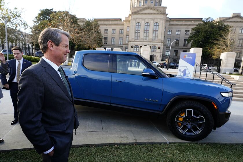 FILE - Georgia Gov. Brian Kemp smiles as he stands next to a Rivian electric truck during a ceremony to announce that the electric truck maker plans to build a $5 billion battery and assembly plant east of Atlanta projected to employ 7,500 workers, on Dec. 16, 2021, in Atlanta. A Georgia judge on Thursday, Sept. 29, 2022, rejected an agreement that would have provided a huge property tax break to Rivian Automotive, clouding the upstart electric truck maker's plans to build a plant east of Atlanta. (AP Photo/John Bazemore, File)
