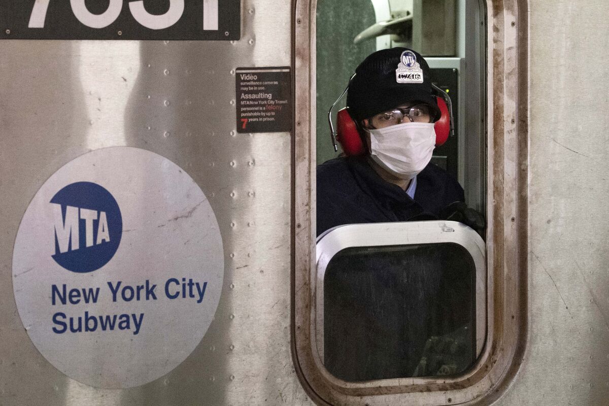 FILE — In this April 18, 2020 file photo, a subway conductor wears a face mask as the train is in a station, in the Bronx borough of New York. New York Gov. Andrew Cuomo and New York City Mayor Bill de Blasio have scheduled competing news conferences Monday, Aug. 2, 2021, amid rising COVID-19 case counts attributed to the highly contagious delta variant of the virus. (AP Photo/Mark Lennihan, File)