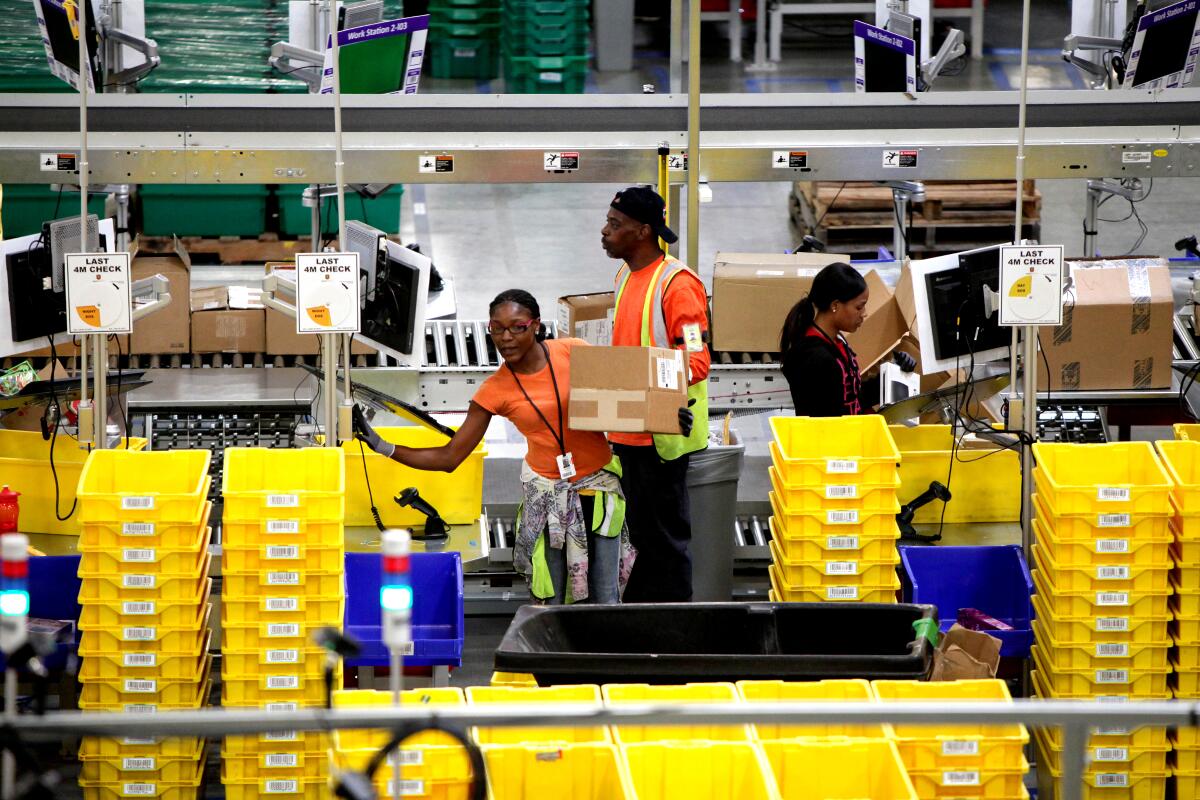 Workers in a warehouse are surrounded by yellow bins.