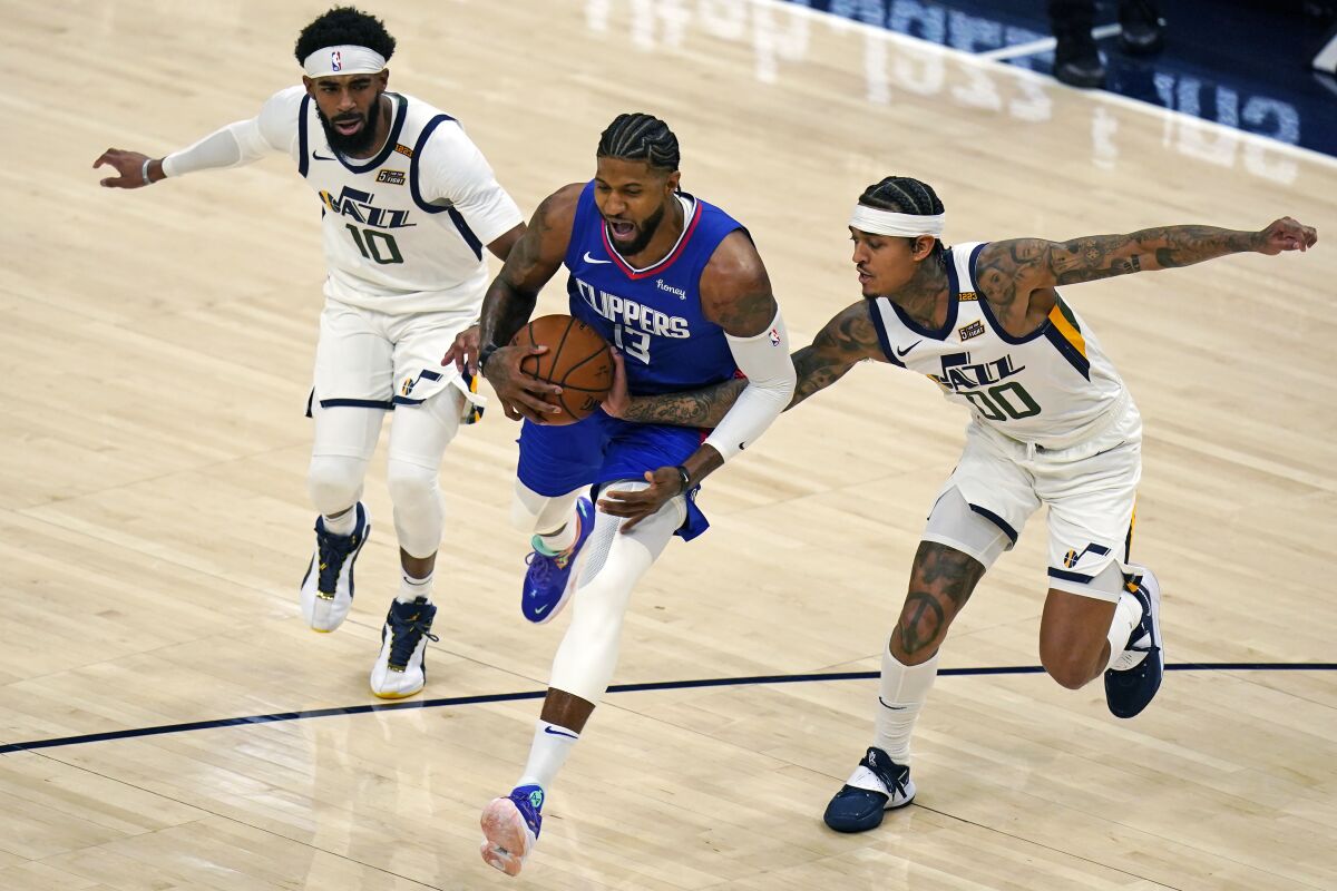 Clippers forward Paul George drives past Utah guards Mike Conley (10) and Jordan Clarkson (00).