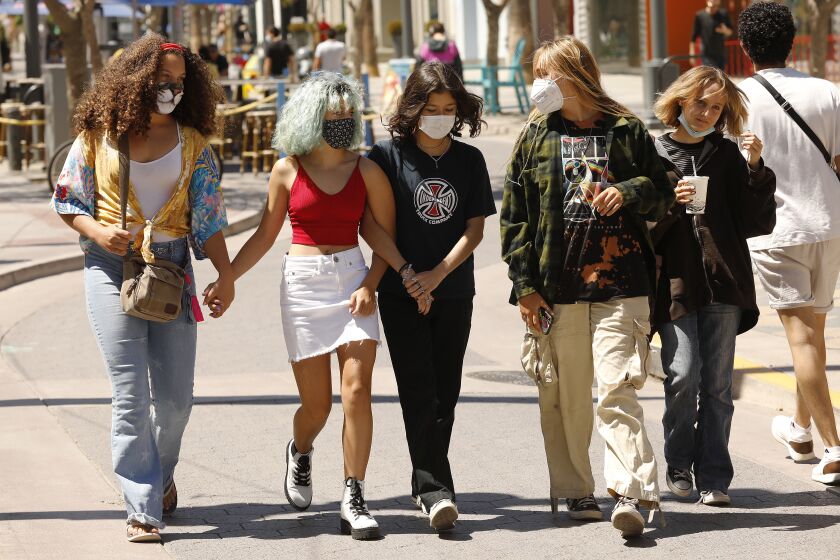 SANTA MONICA, CA - AUGUST 03: Alma, Ruby, Sian, Camille and Evelyn, left to right, join pedestrians of all ages with and without masks walking the Third Street Promenade in Santa Monica Tuesday, August 3, 2021 as Californians and visitors react to the grey space we're in with COVID, lax restrictions and breakthrough cases. Third Street Promenade on Tuesday, Aug. 3, 2021 in Santa Monica, CA. (Al Seib / Los Angeles Times).