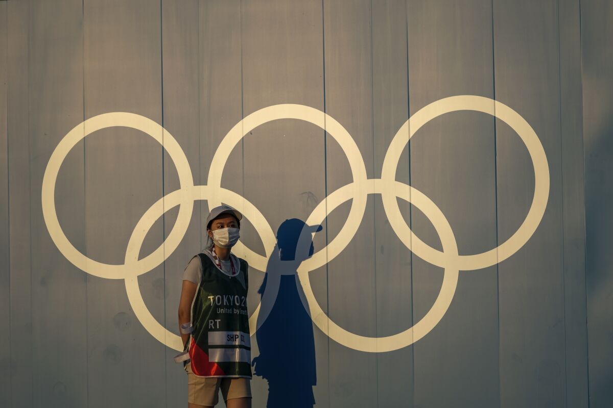FILE - A volunteer walks past the Olympic rings ahead of the 2020 Summer Olympics, in Tokyo on July 22, 2021. Japan's northern city of Sapporo on Monday, June 6, 2022, rejected holding a referendum to give voters a choice over bidding for the 2030 Winter Olympics. The city's assembly, controlled by Japan's Liberal Democratic Party, which is also in charge of the national government, turned down having a public vote. Its meeting was streamed online. (AP Photo/Petros Giannakouris, File)