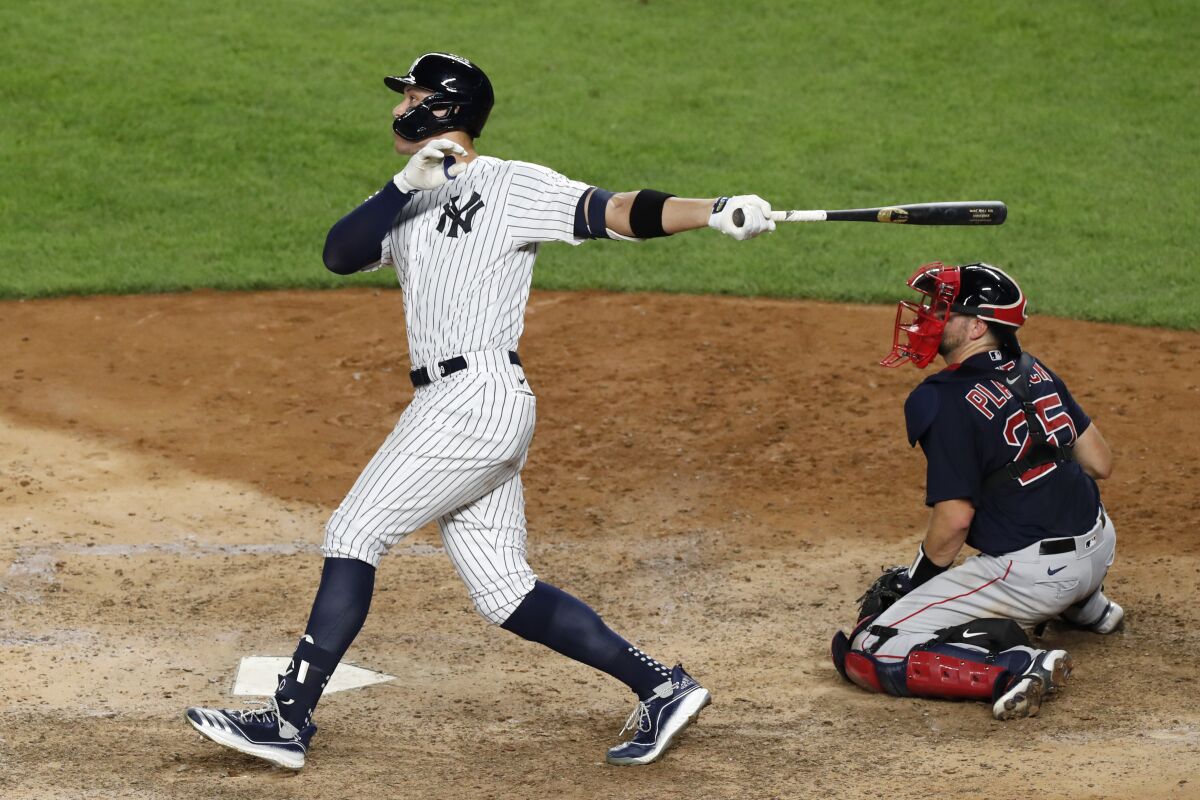New York Yankees' Aaron Judge follows through on an eighth-inning, two-run home run against the Boston Red Sox in a baseball game Sunday, Aug. 2, 2020, at Yankee Stadium in New York. Red Sox catcher Kevin Plawecki is at right. (AP Photo/Kathy Willens)