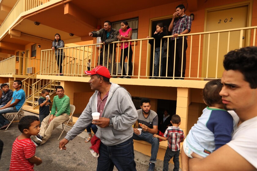 Jose Oscar Martinez Cruz of El Salvador, right, holds his 9-month-old son, Carlos, as Orlando Guifaro of Honduras, in red hat, reaches for his son Justin, 5, at an El Paso motel housing Central American families.
