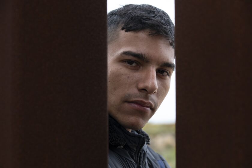 Jean Carlos, 24, of Colombia, waits between the border walls