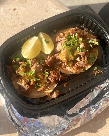 Two carnitas tacos in a to-go container