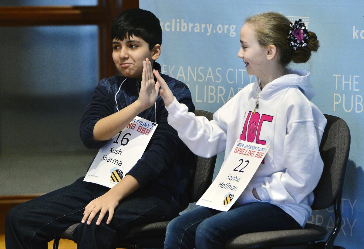 Kush Sharma, left, high-fives Sophia Hoffman before the continuation of the Jackson County Spelling Bee at the Central Library in Kansas City, Mo. on Saturday. Two weeks ago, the bee ran out of words after the two eliminated 23 other contestants and went another 47 rounds against each other.