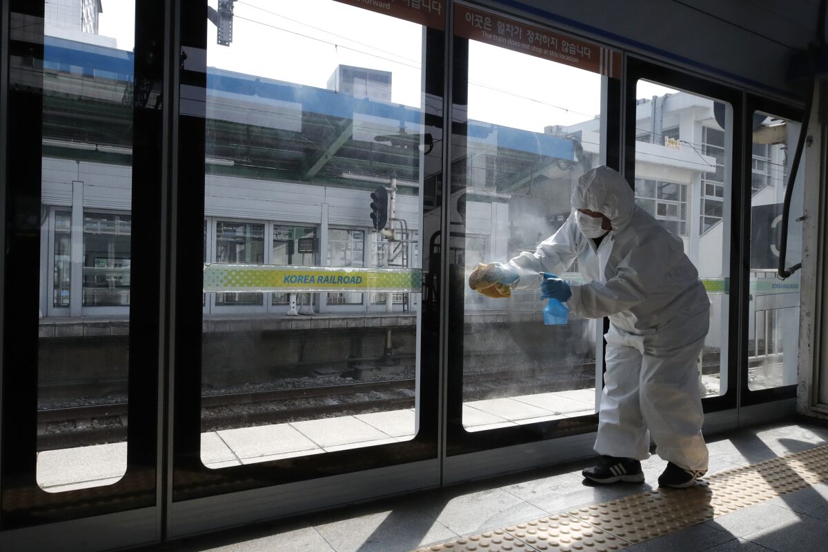 A worker wearing protective gears disinfects as a precaution against the coronavirus at the subway station in Seoul.