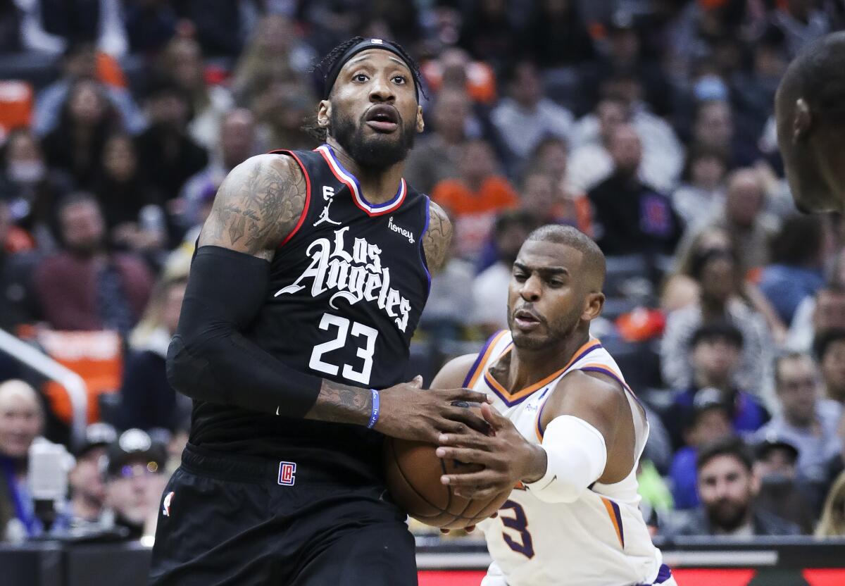 Phoenix Suns guard Chris Paul lunges for the ball while Clippers forward Robert Covington drives to the basket.