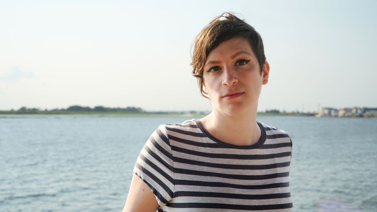 A woman in a striped shirt before an ocean