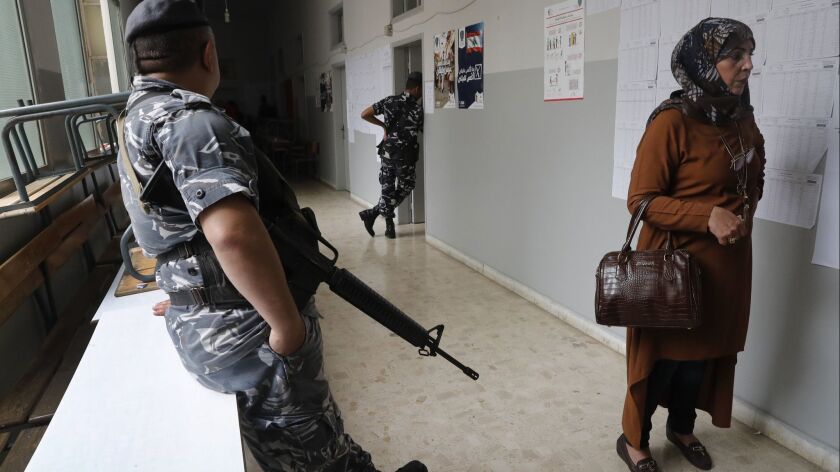 A police officer stands guard as a woman waits to cast her vote Sunday in Lebanon's parliamentary elections