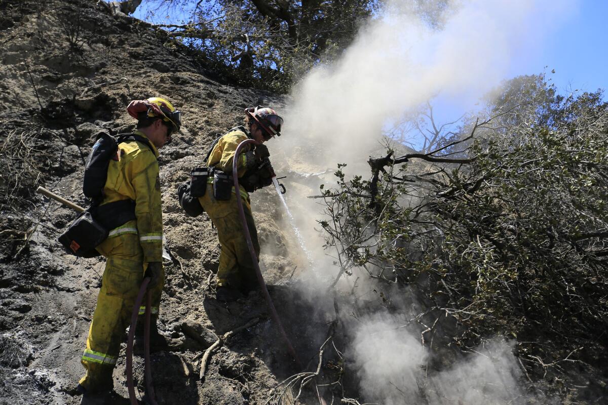 Cal Fire-San Diego firefighter Andrew Russell, left, and Cpt. Angel Hendrie spend their 12th day on the road fighting fires and mopping up the remnants of the Sage fire in Santa Clarita.