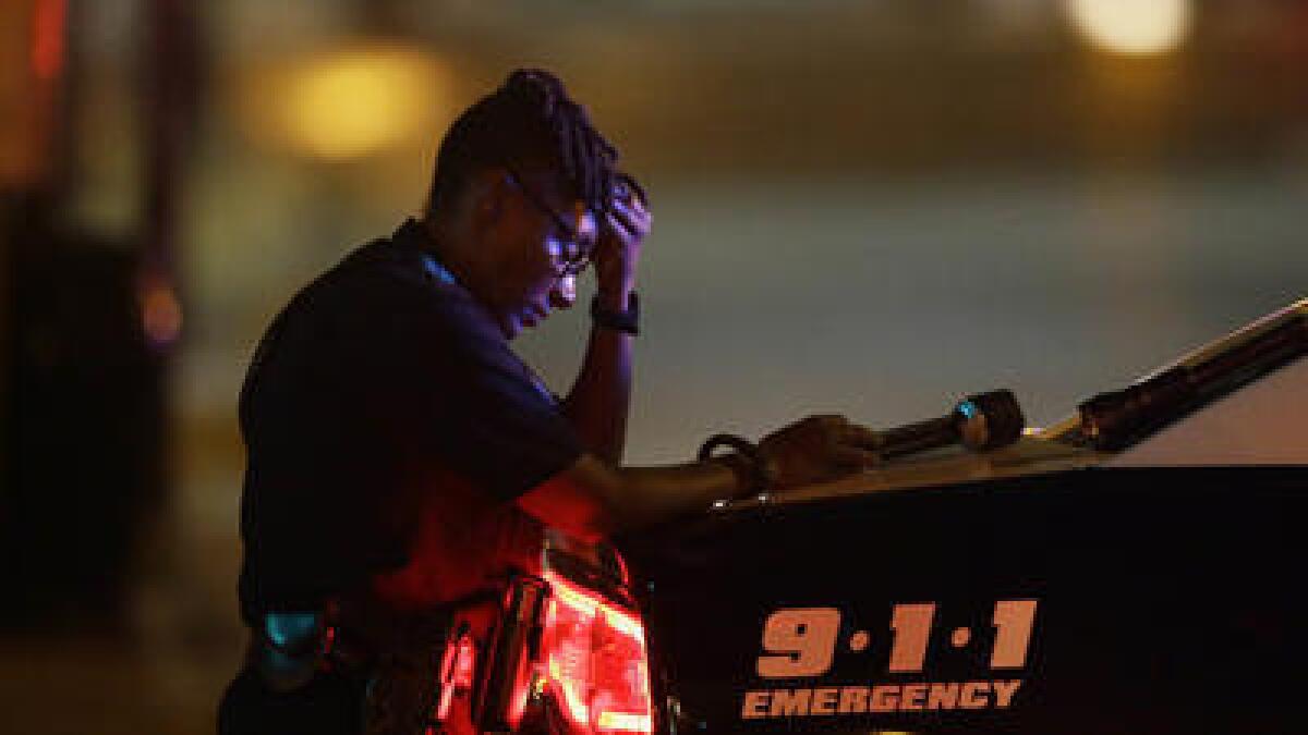 A Dallas police officer, who did not want to be identified, takes a moment as she guards an intersection after the deadly shooting.