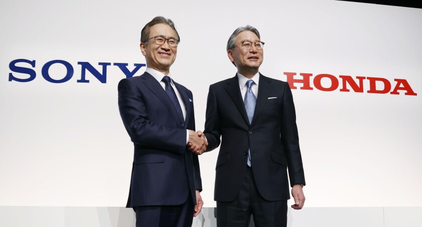 Sony Group Corp.'s Chief Executive Kenichiro Yoshida, left, and Honda Motor Co.'s Chief Executive Toshihiro Mibe, right, shake hands at a press conference in Tokyo Friday, March 4, 2022. Two big names in Japanese electronics and autos are joining forces to produce an electric vehicle together. Sony Group Corp. and Honda Motor Co. agreed to set up a joint venture this year to start selling an electric vehicle by 2025, both sides said Friday. (Jun Hirata/Kyodo News via AP)