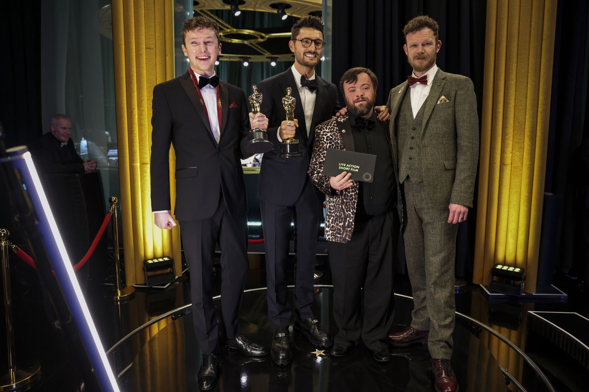 four men in tuxes with two holding oscars