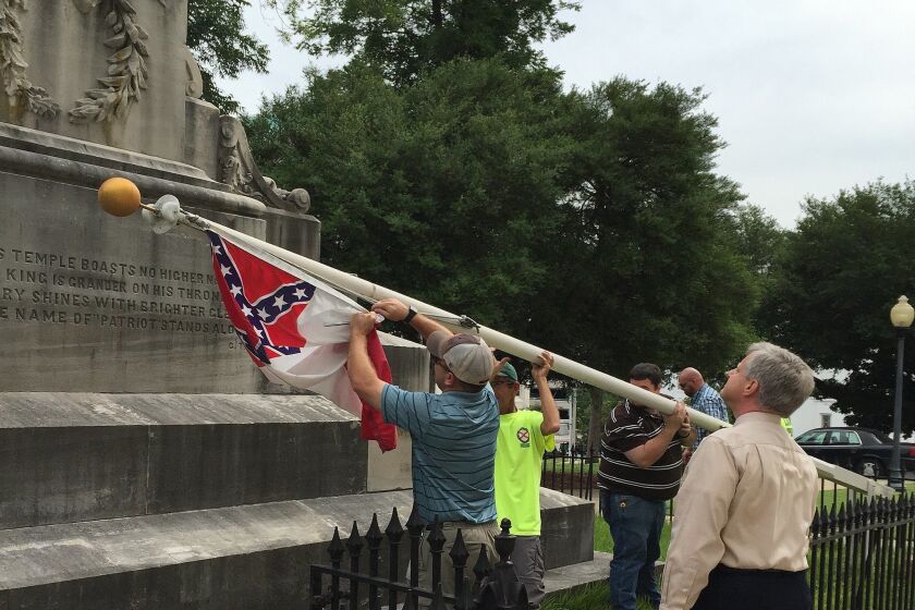State workers take down a Confederate national flag on the grounds of the state Capitol, Wednesday, June 24, 2015, in Montgomery, Ala. Alabama Gov. Robert Bentley ordered Confederate flags taken down from a monument at the state Capitol. (AP Photo/Martin Swant)