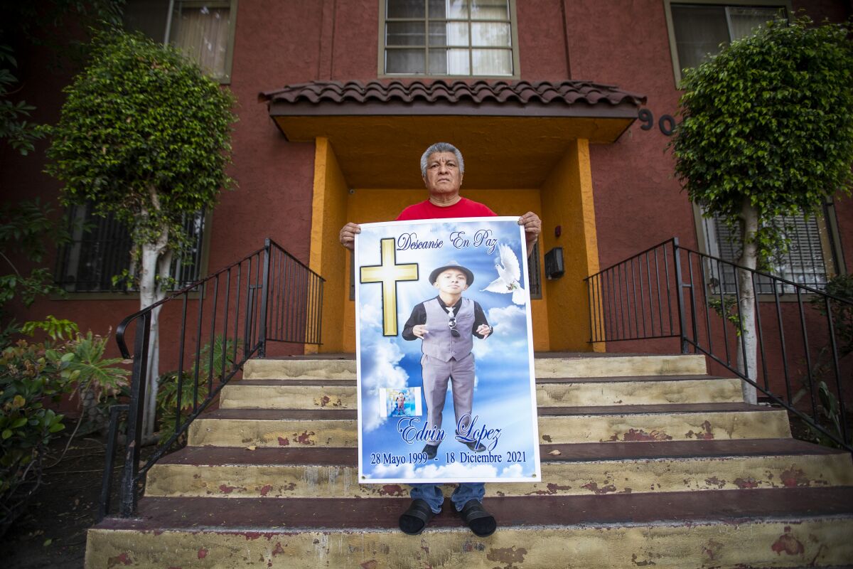 A man holding a poster on the steps outside a building