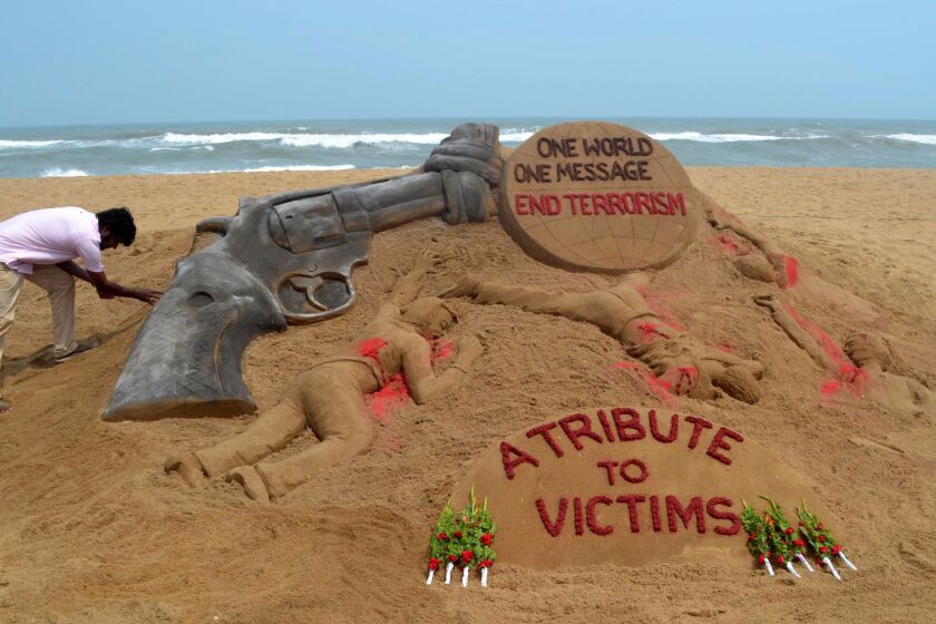 Indian sand artist Sudarsan Pattnaik puts the finishing touches on a sand sculpture at Puri Beach, India, on Monday, following the attack on a gay nightclub in Orlando, Fla.