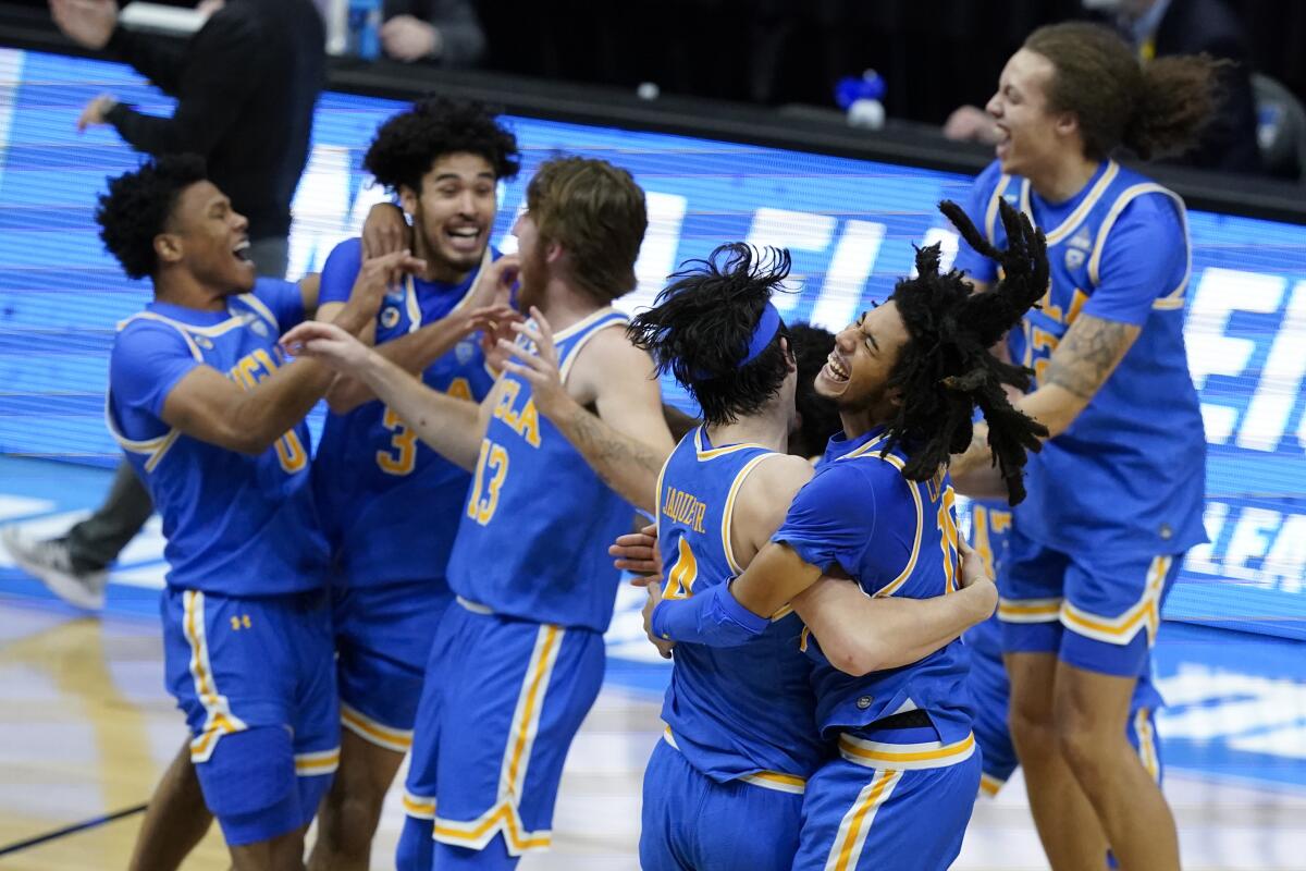 UCLA guard Tyger Campbell celebrates with teammates, including Jaime Jaquez Jr., after an Elite 8 win over against Michigan 