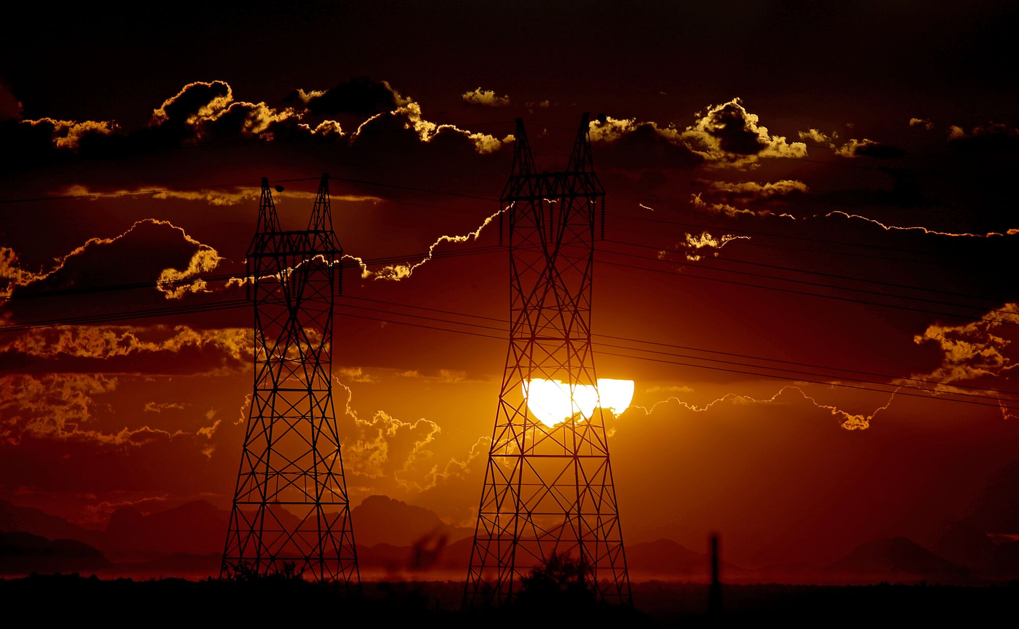 A sun setting behind power lines