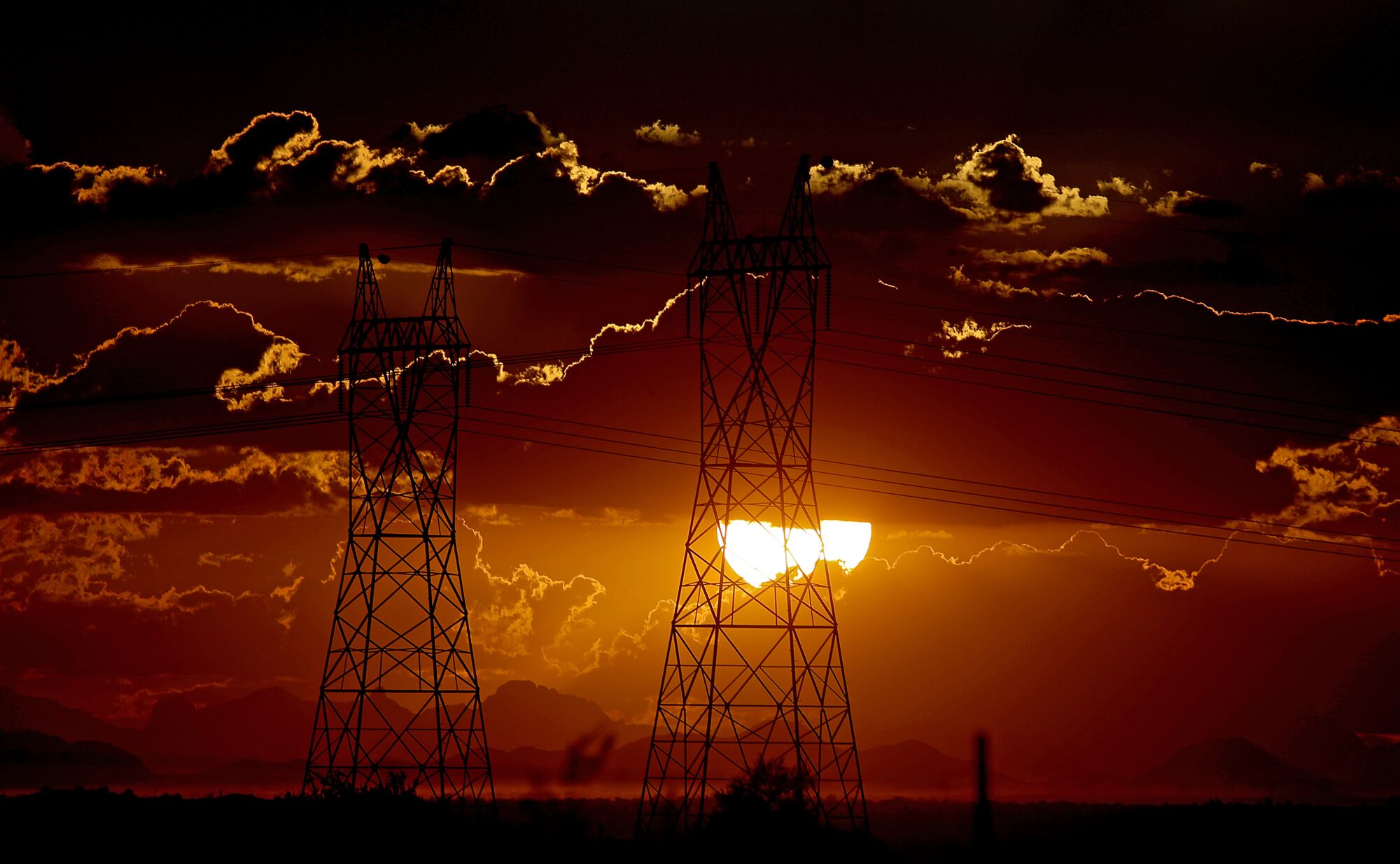 A sun setting behind power lines 