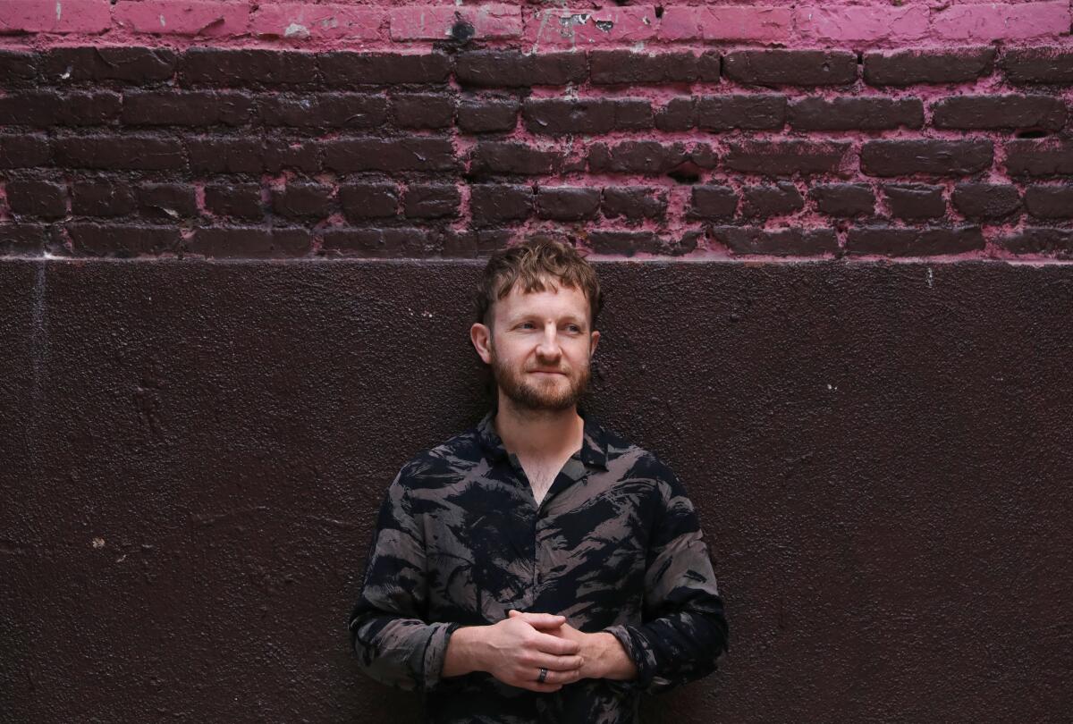 A man in front of a  brick wall