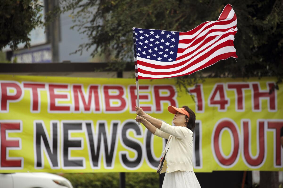 Eileen Chang waves an American flag at a recall election rally in Rowland Heights.
